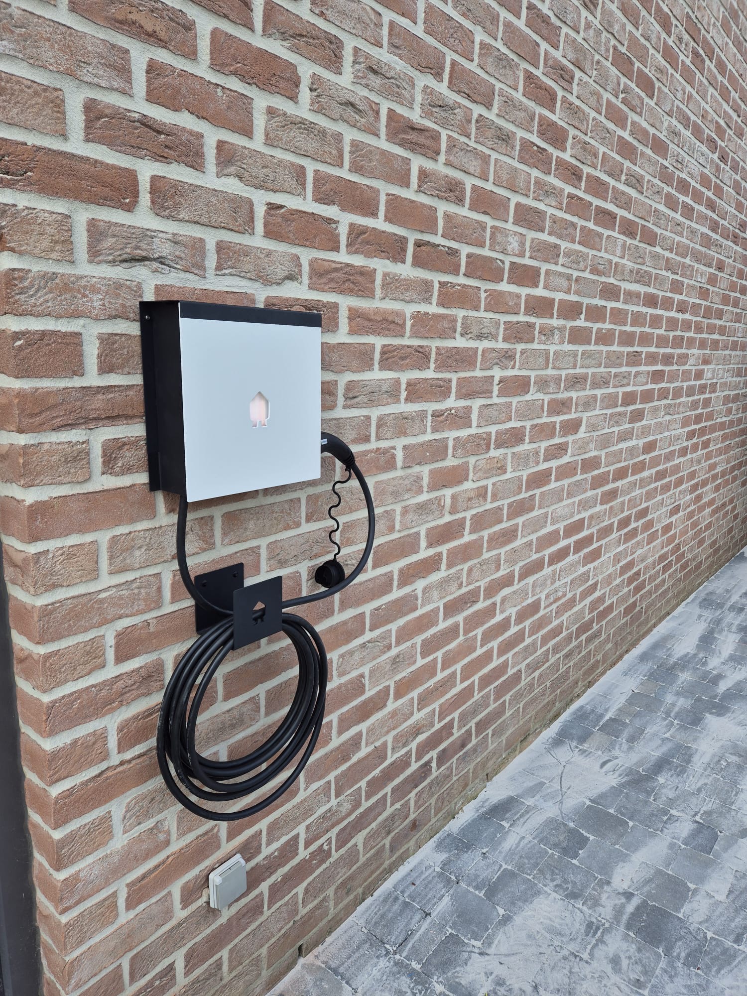 Borne de recharge pour véhicule électrique installée sur façade en briques