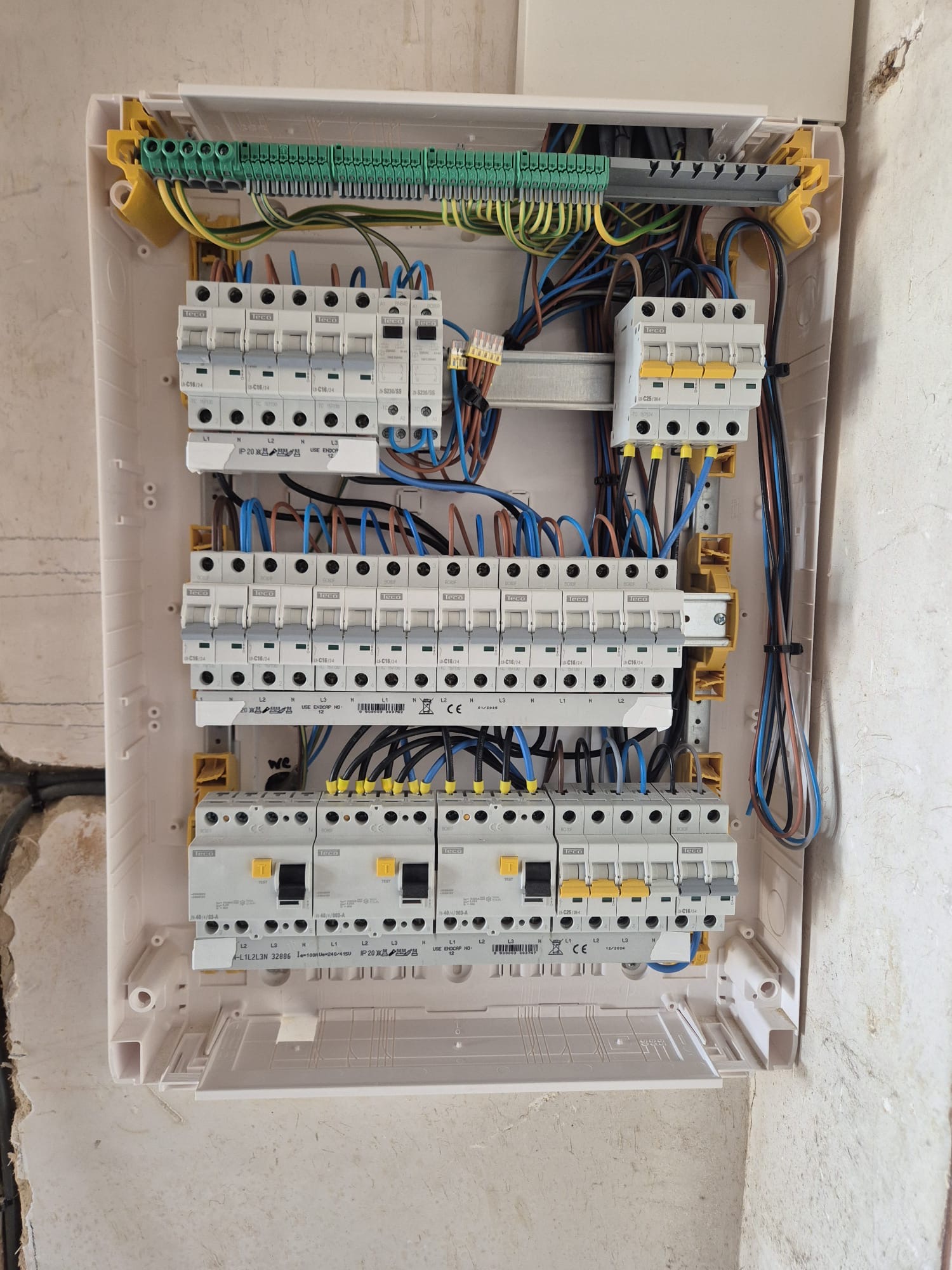 Câblage en cours d'un coffret électrique triphasé avec borniers de terre